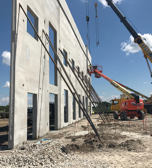 Cranes and poles supporting a concrete wall that is a part of Ignatius Press's new warehouse.